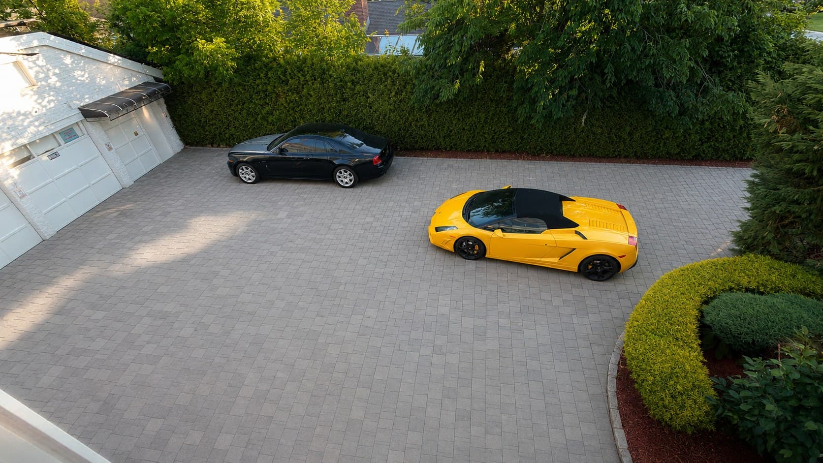 A Rolls-Royce and a Lamborghini on the estate's private driveway.